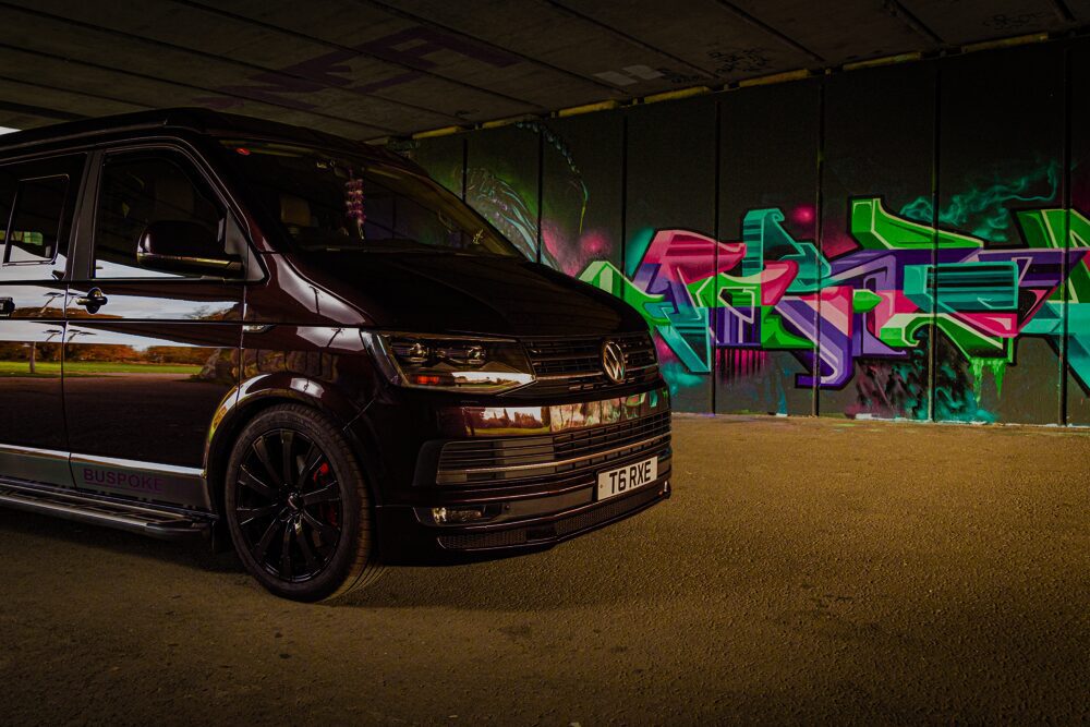Van parked near colorful graffiti-covered wall.