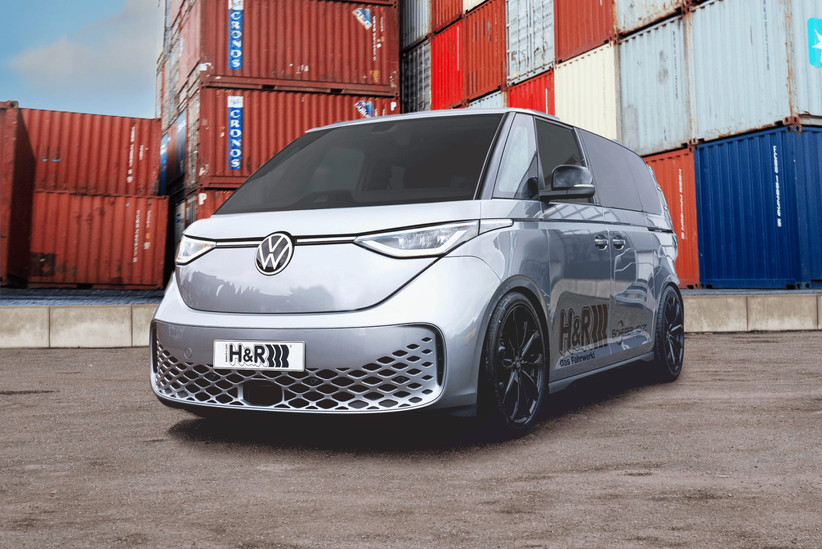Silver van in front of shipping containers.