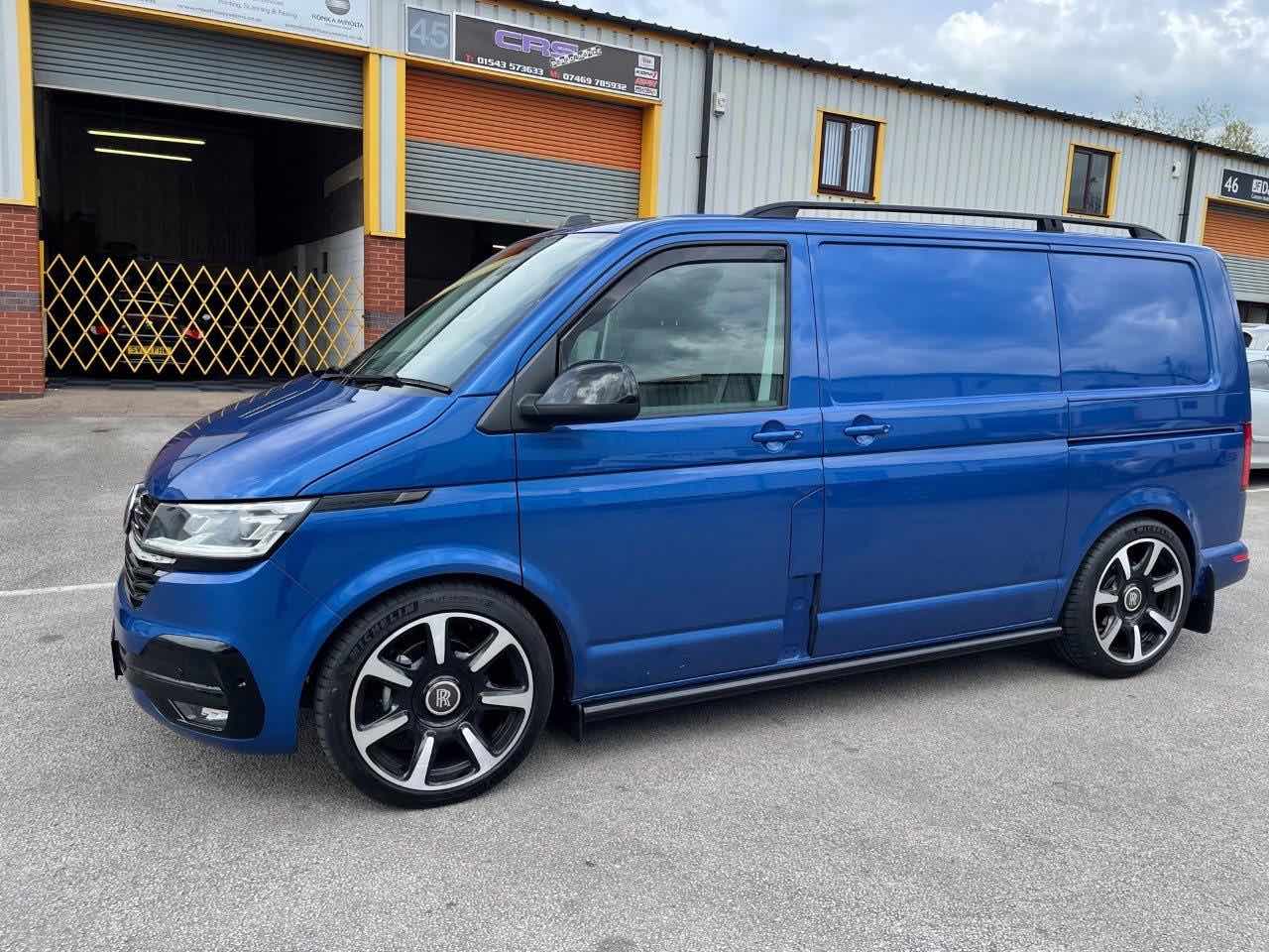 Blue van parked near industrial building.